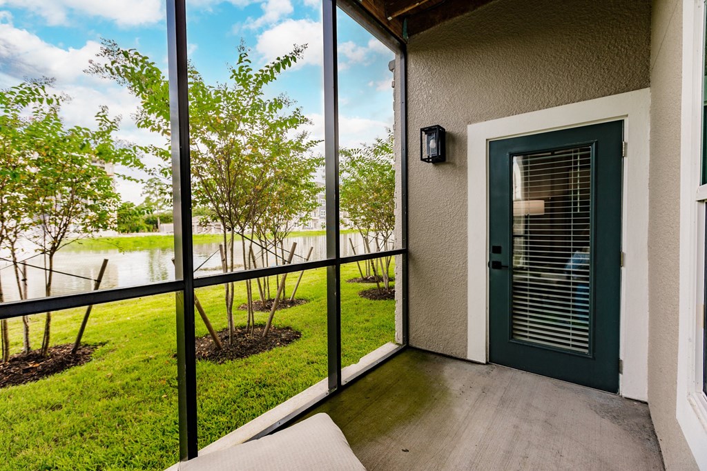 a patio with a green door and a view of a lake and trees