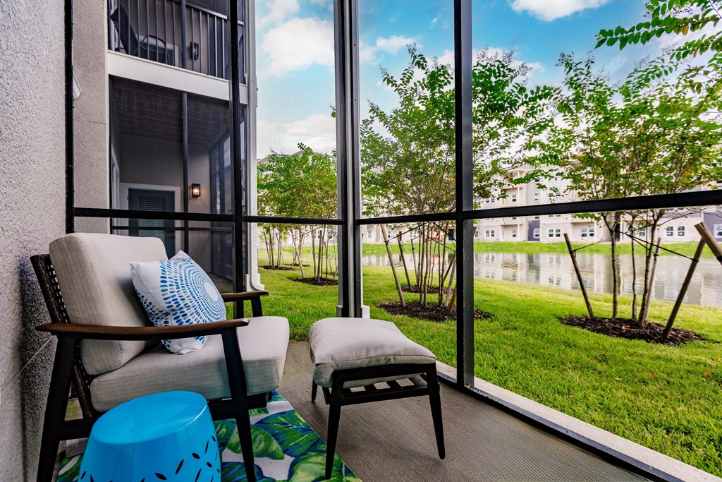 a balcony with a couch and a chair and a view of the grass