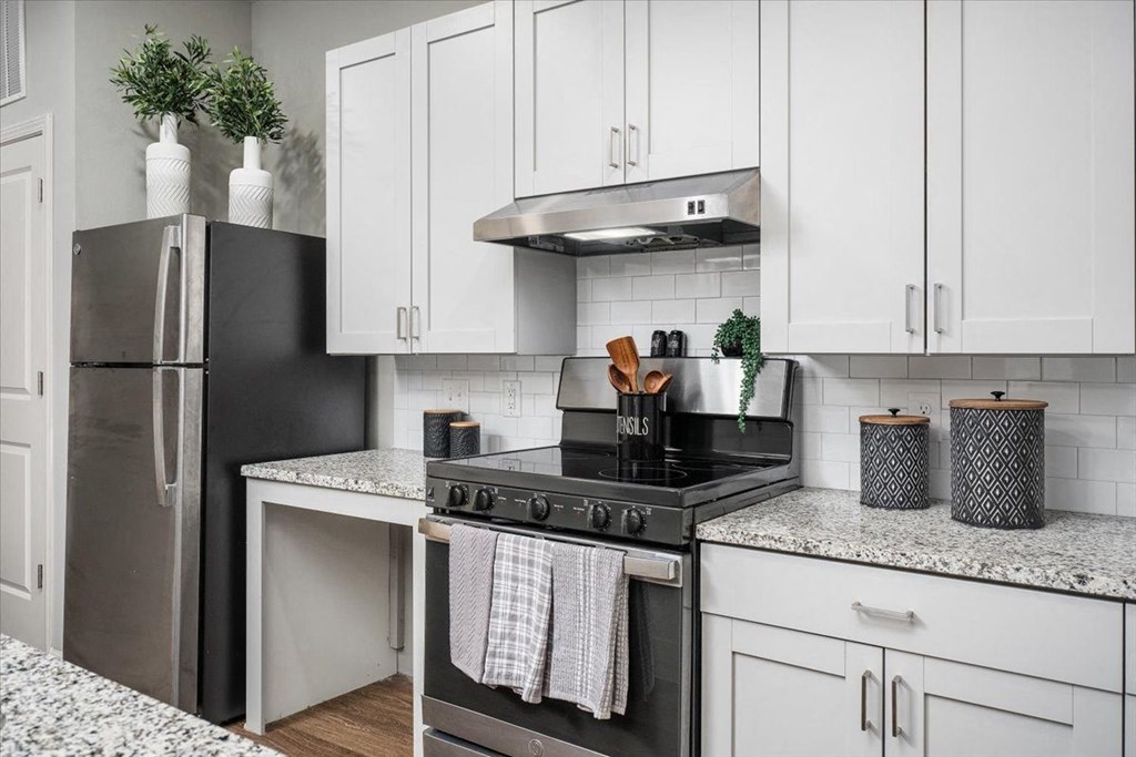 a white kitchen with white cabinets and a black stove