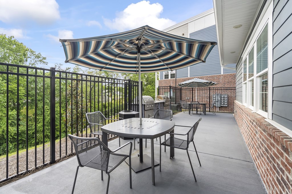 A patio with a table and chairs under a striped umbrella.