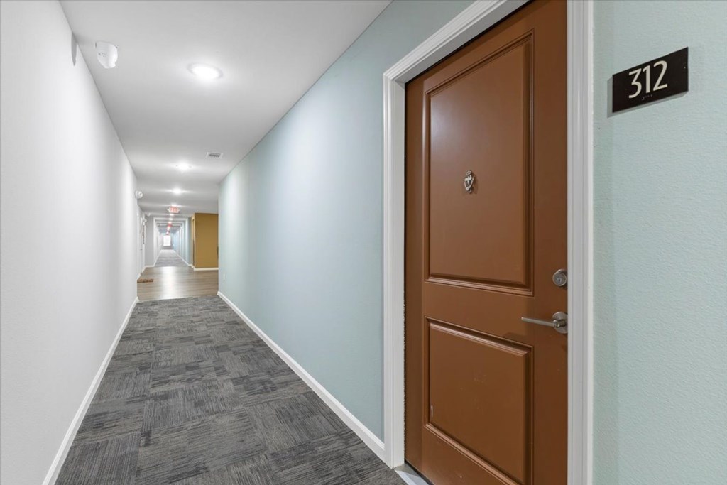 A hallway with a brown door and a sign that says 312.