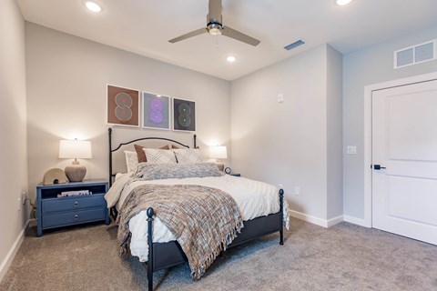 a bedroom with a bed and a ceiling fan at  a living room with tables and chairs and a ceiling fan