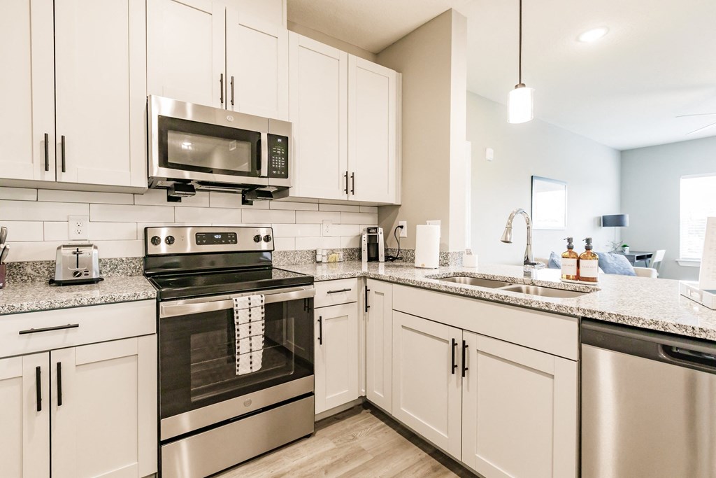 a kitchen with stainless steel appliances and white cabinets at Vantage Luxury Apartments in  Cape Coral, FL