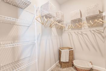 a walk in closet with a white shower and a basket on the floor