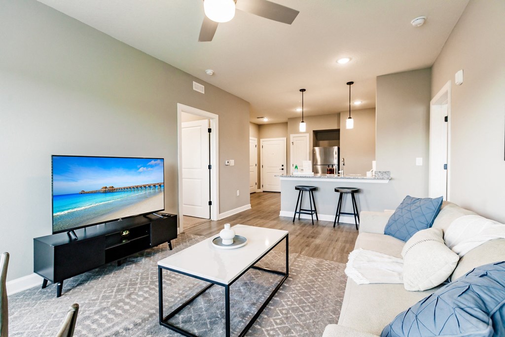 a living room with a coffee table, a couch, and a kitchen in the background