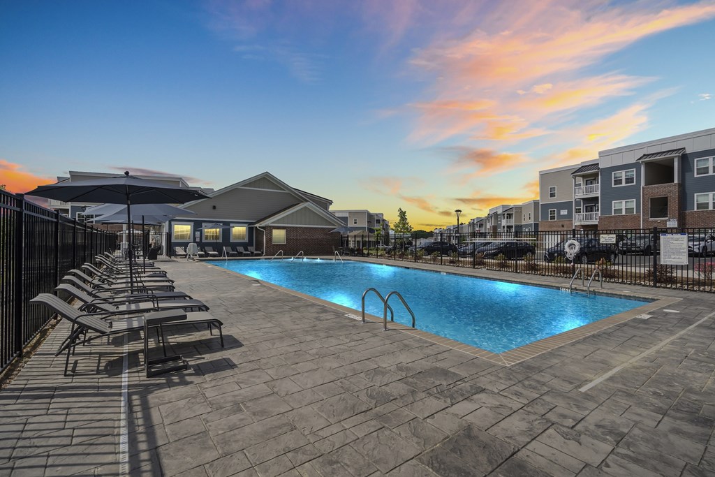 A swimming pool surrounded by lounge chairs and umbrellas at a resort.