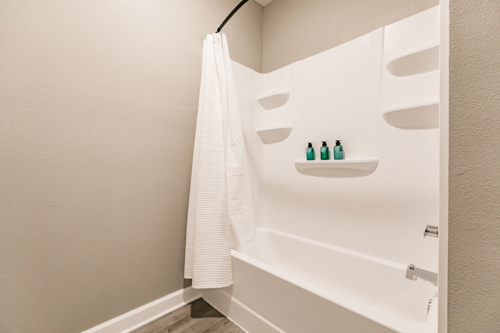 a bathroom with a tub and a shower and a white shower curtain