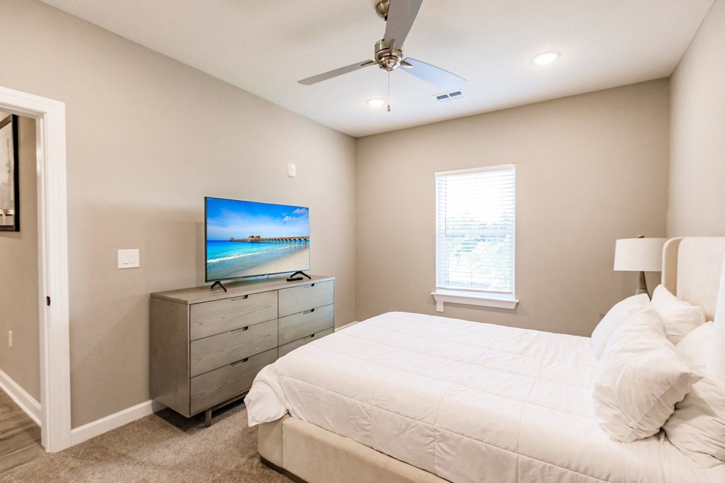 the master bedroom has a large bed and a tv