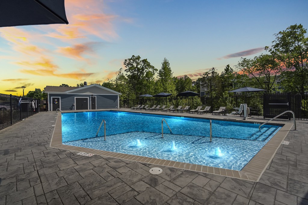 A large outdoor swimming pool with a sunset sky in the background.