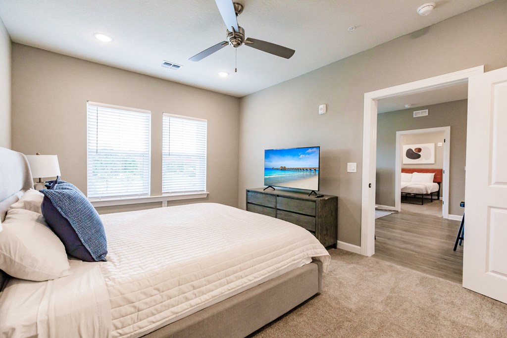 a bedroom with a bed, a tv, and two windows at Vantage Luxury Apartments in  Cape Coral, FL
