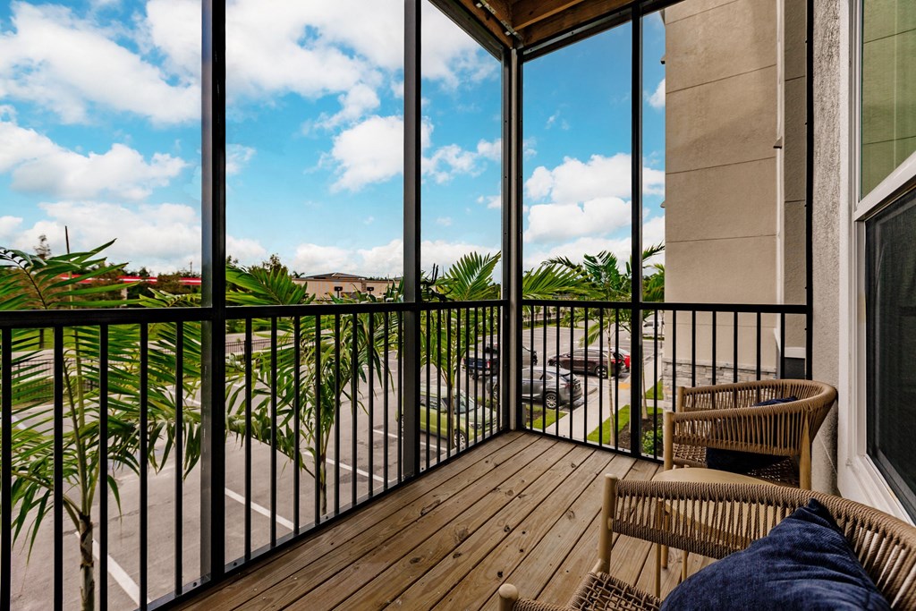 a balcony with two chairs and a view of a palm tree