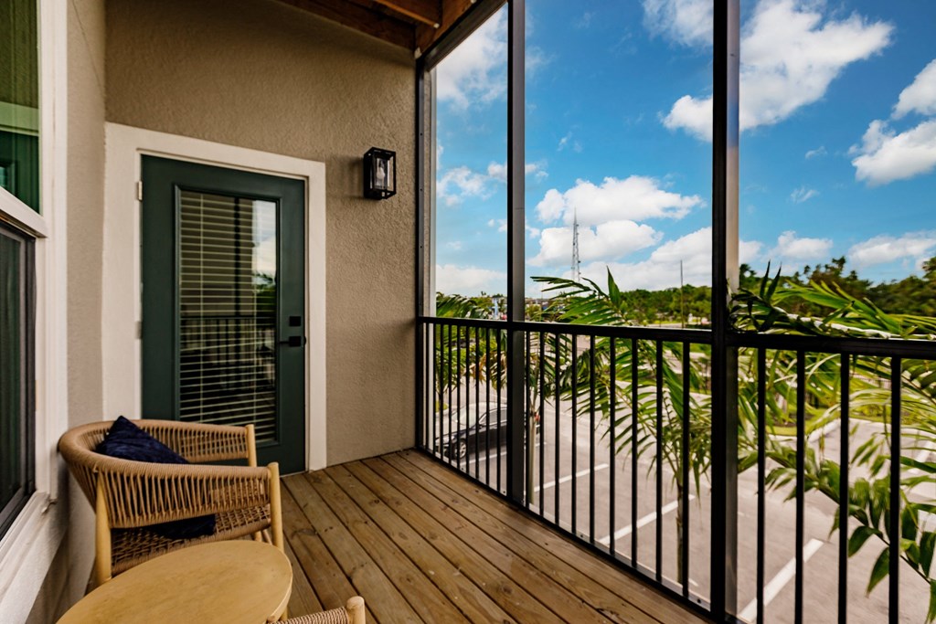 a screened in balcony with a view of the ocean and a chair and a table