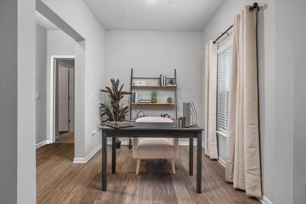 a bedroom with a desk with a chair and a window