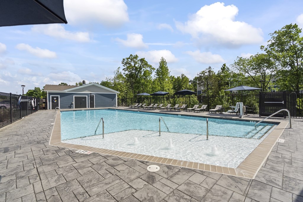 A large outdoor swimming pool surrounded by a stone patio.