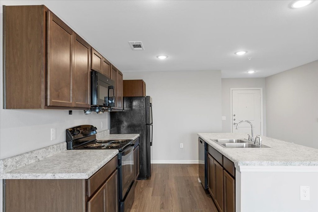 A kitchen with brown cabinets and black appliances.