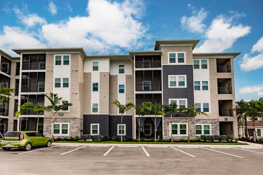 an apartment building with a parking lot and a green car in front of it