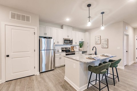 an open kitchen with an island and stainless steel refrigerator