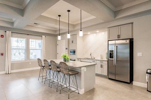 a kitchen with a large island with bar stools and a stainless steel refrigerator