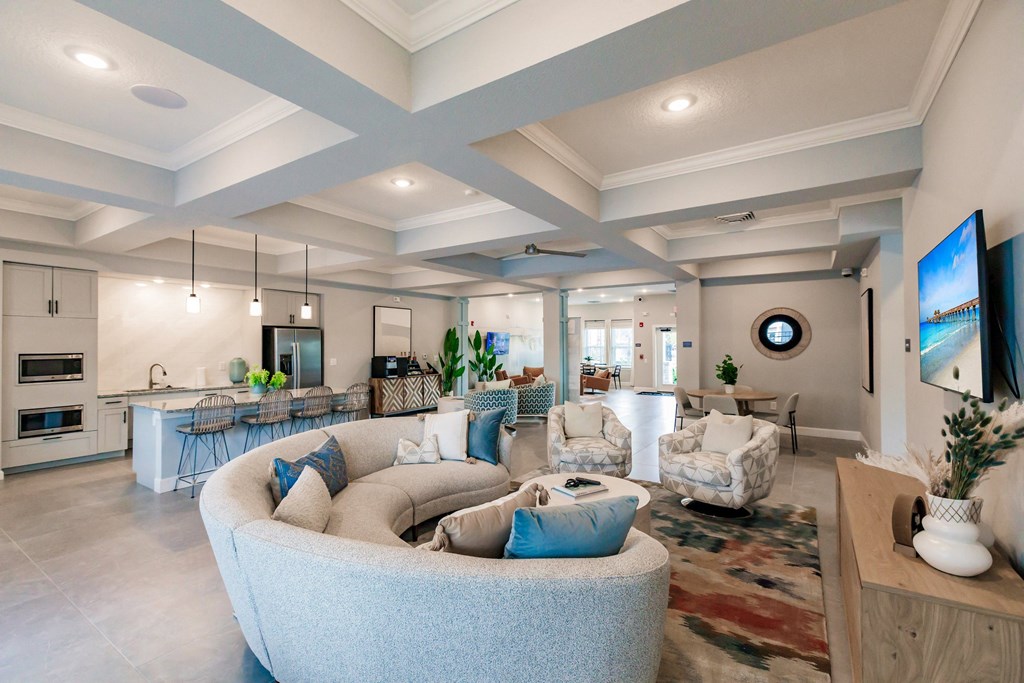 lounge area with a large couch, chairs, and a kitchen in the background at Vantage Luxury Apartments in  Cape Coral, FL