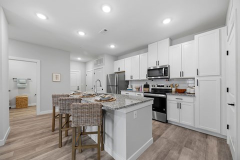 A kitchen with white cabinets and a grey island.