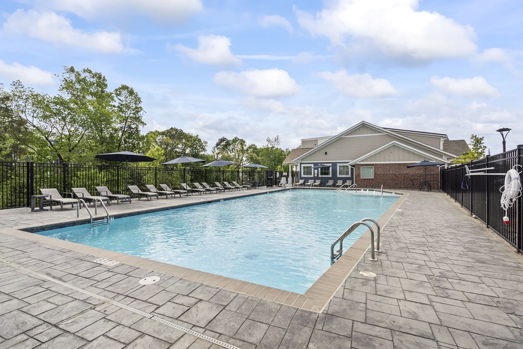 A pool surrounded by a black fence and a building in the background.