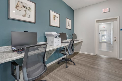 A room with a desk, chairs and computers.