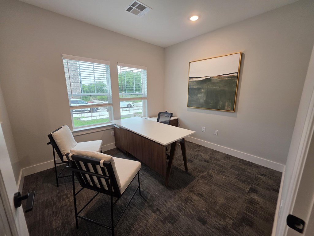 A room with a desk, chair, and a painting on the wall.