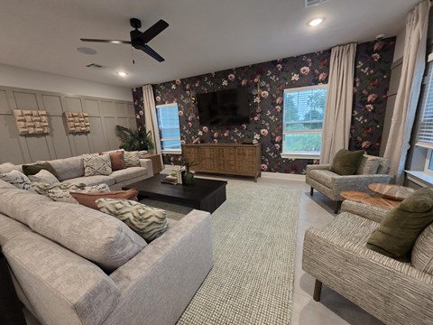 A living room with a grey sofa, a green armchair, and a television mounted on the wall.