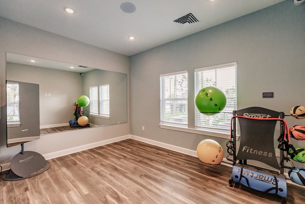 a workout room with a treadmill and weights and a window