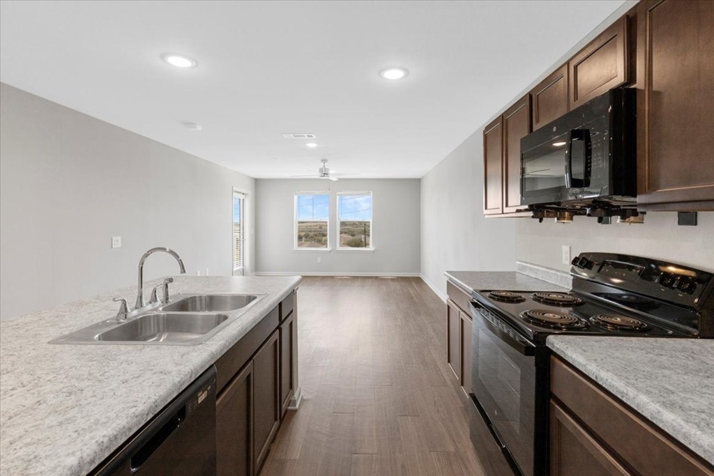 A kitchen with dark wood cabinets and a stainless steel sink.