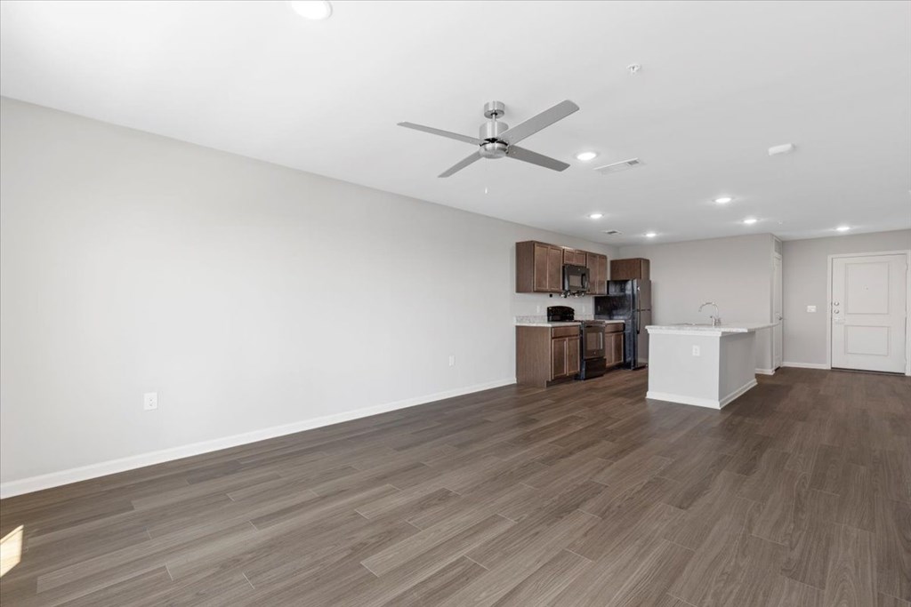 A room with a ceiling fan and wooden flooring.