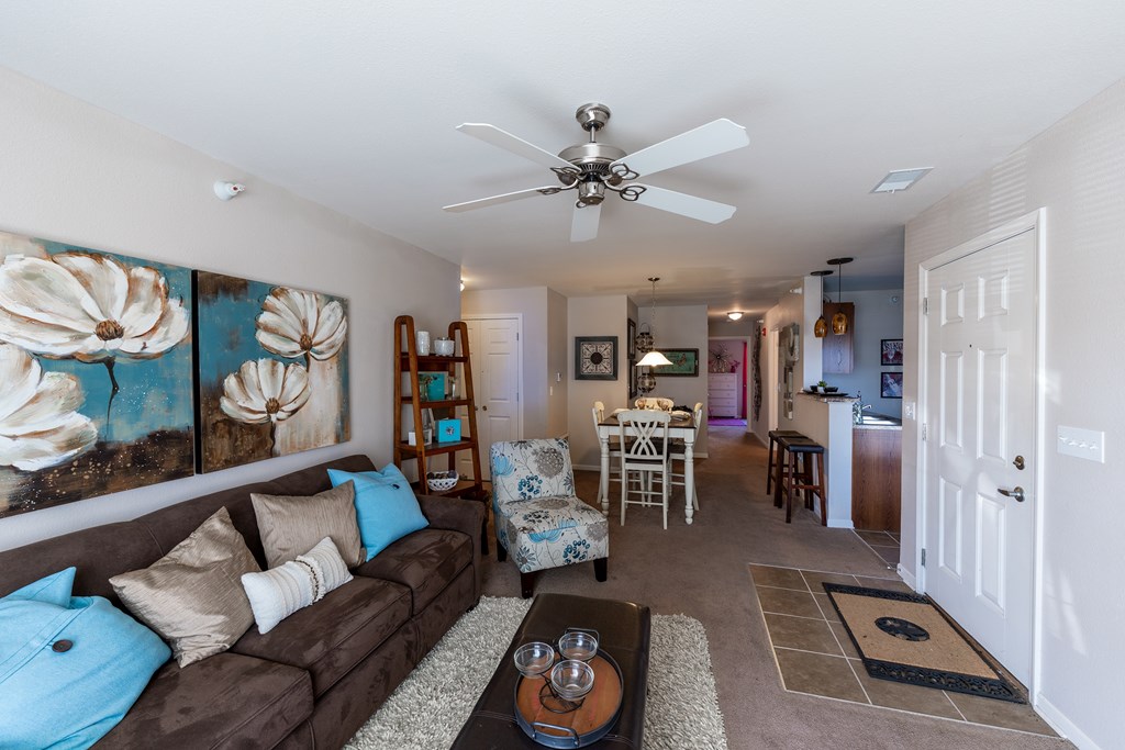 A living room with a brown couch and a ceiling fan.