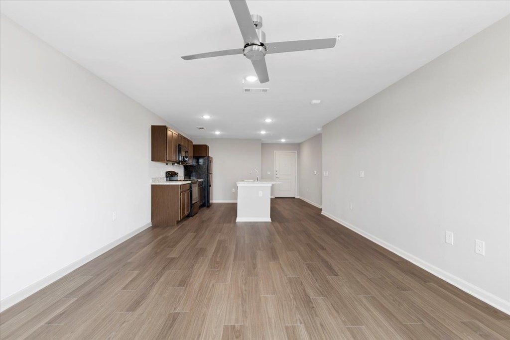 A room with a ceiling fan and wooden flooring.