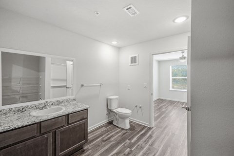 A bathroom with a toilet, sink, and mirror.