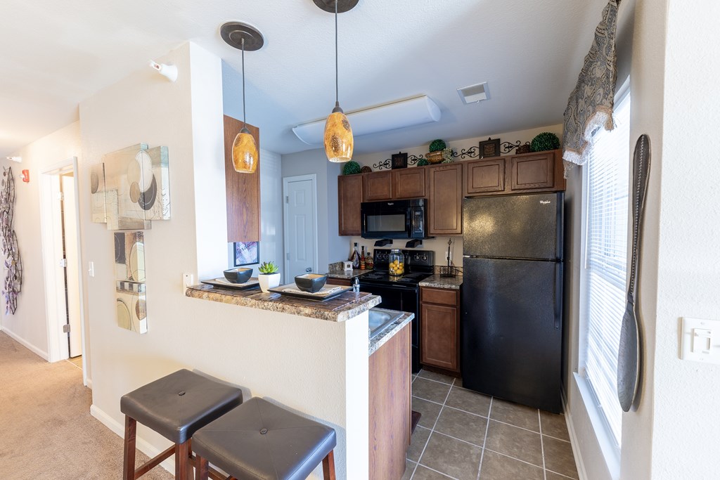 A kitchen with a black refrigerator and wooden cabinets.