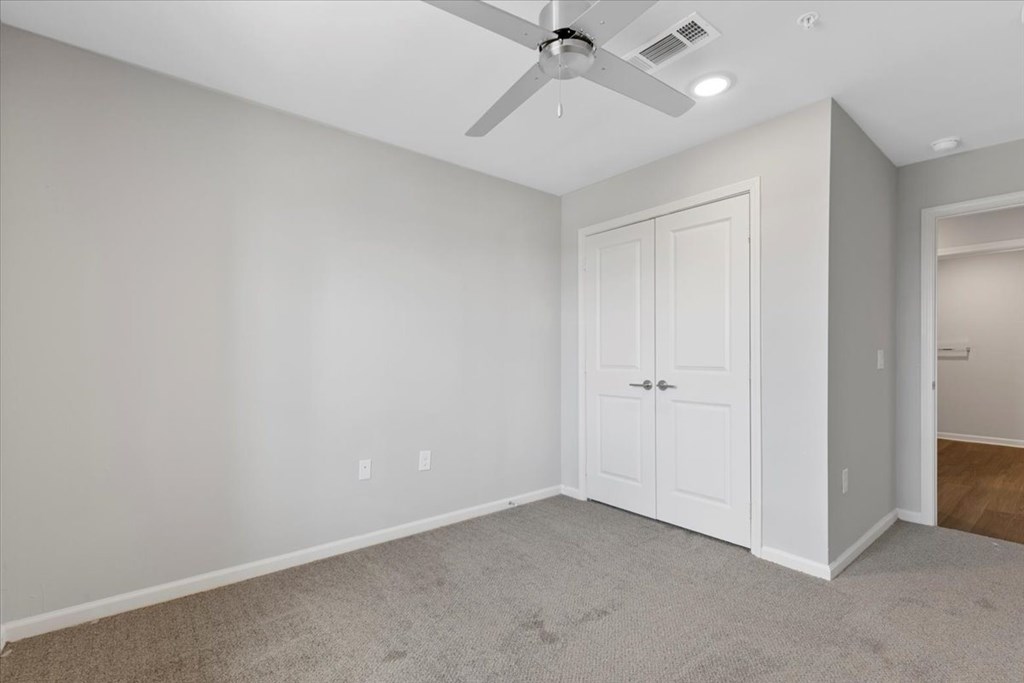 A room with a ceiling fan and a door.