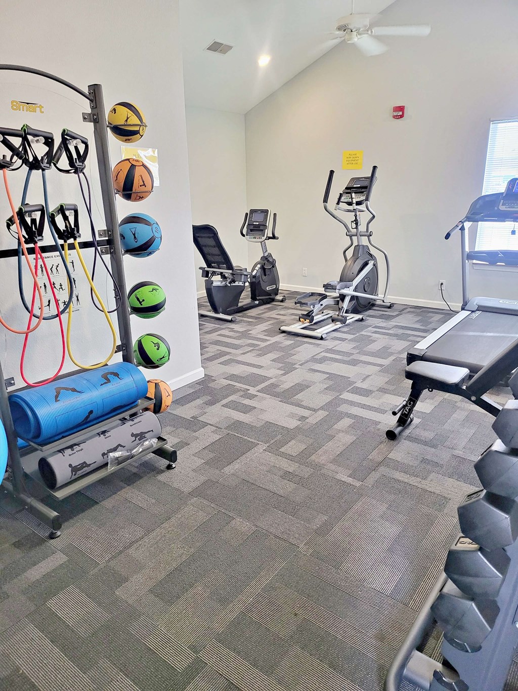 a gym with cardio equipment and weights at the district at highland village apartments