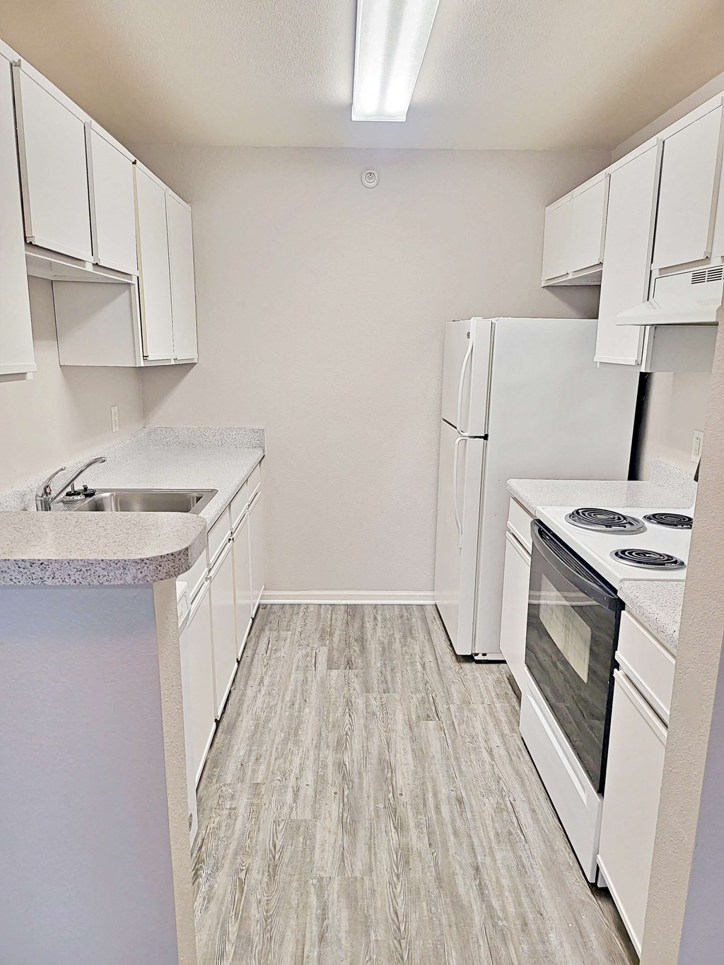 an empty kitchen with white appliances and white cabinets