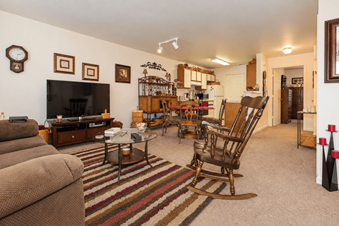 A living room with a brown couch and a wooden rocking chair.