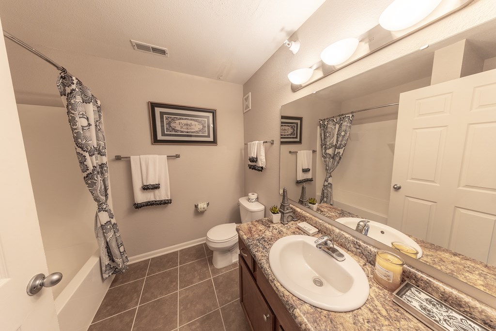 A bathroom with a toilet, sink, and mirror.