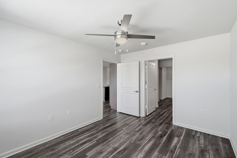 A room with a ceiling fan and wood flooring.