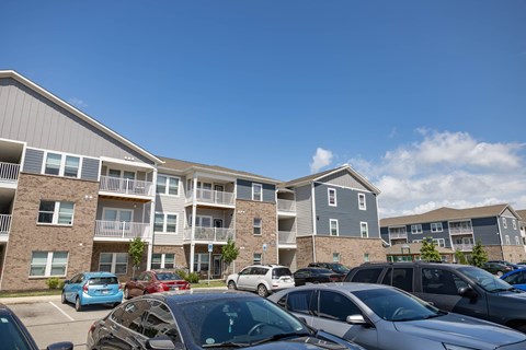 A parking lot with cars and apartment buildings in the background.