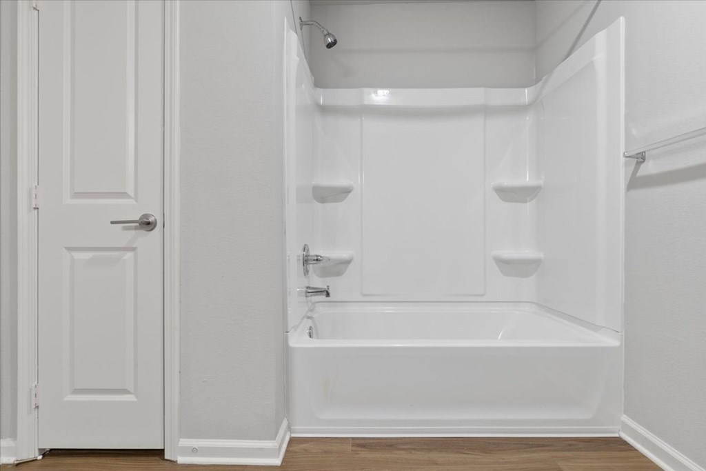 A white bathroom with a tub and a door.