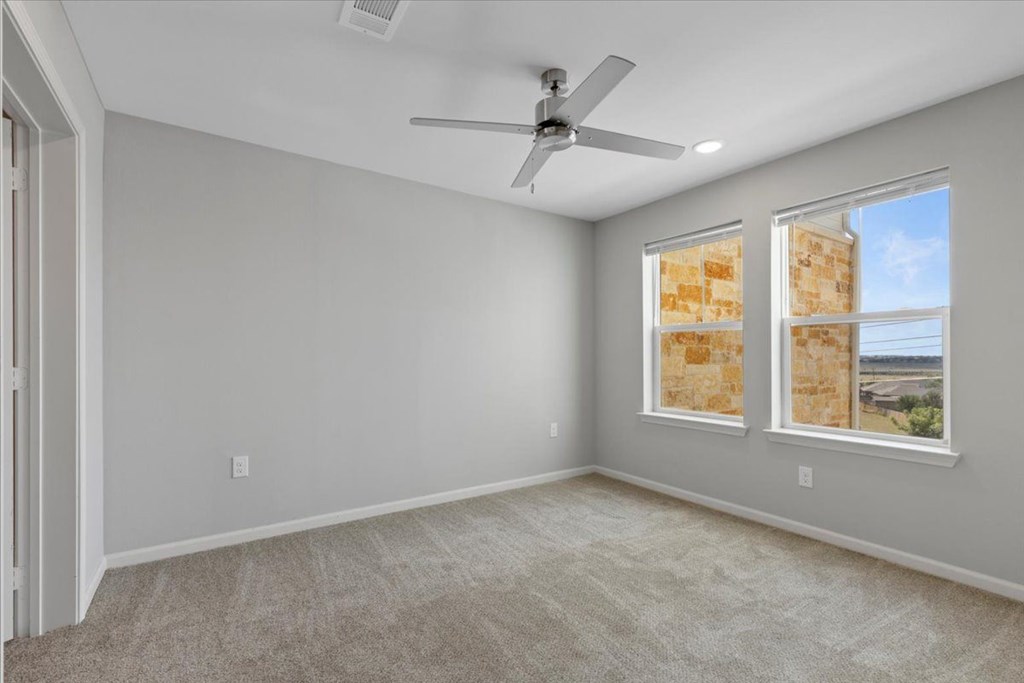 A room with a ceiling fan and two windows.