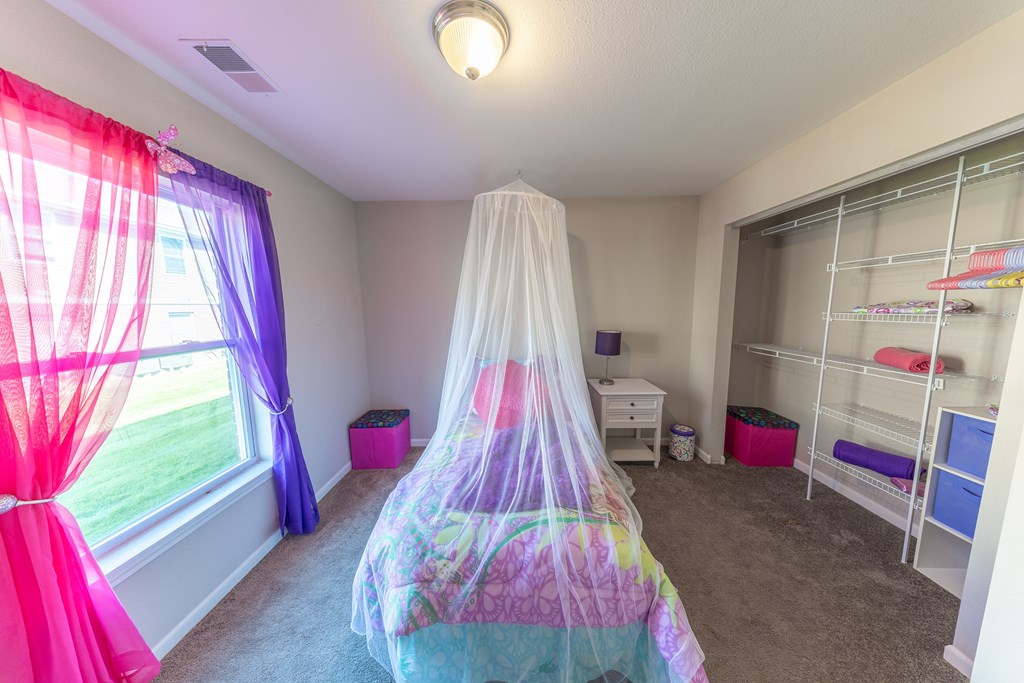 A room with a bed covered in a colorful bedspread and a canopy.