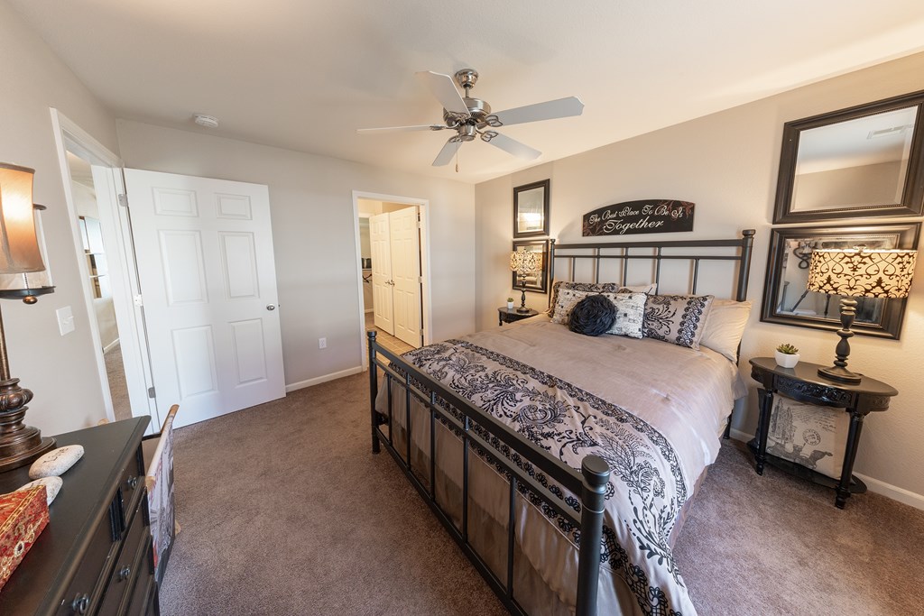 A bedroom with a large bed and a ceiling fan.