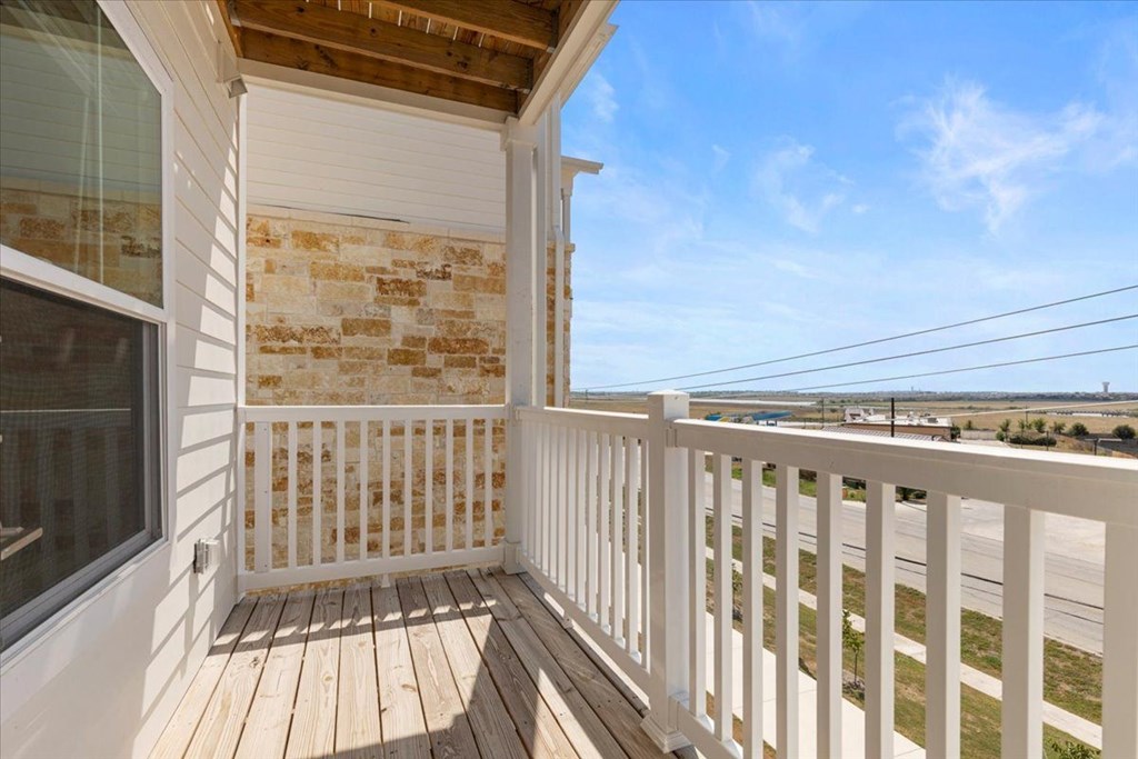 A balcony with a white railing and a wooden floor.