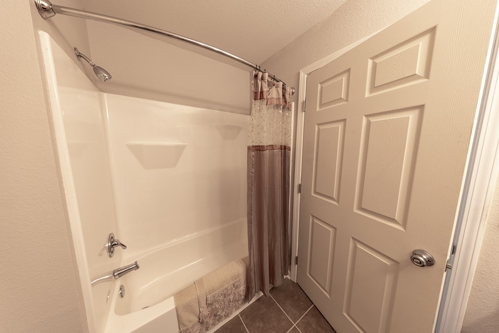 A white bathroom with a shower and a door.