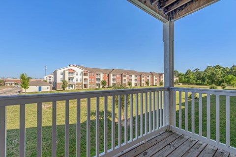 A view from a balcony overlooking a grassy area and apartment buildings.