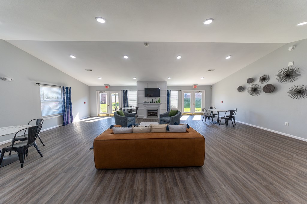 A living room with a brown couch and wooden floors.